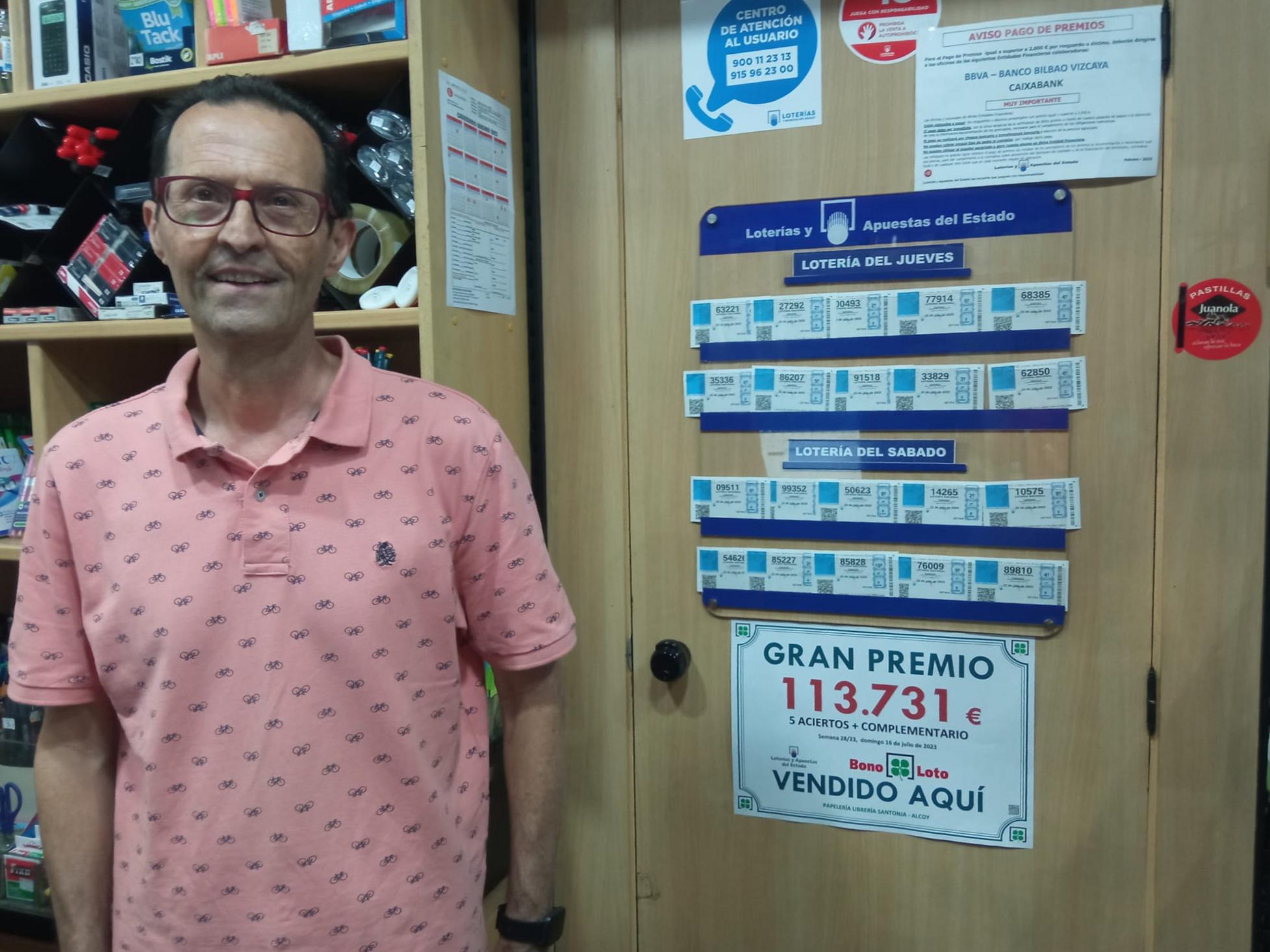 Vicent Santonja, en la papelería Santonja, con el cartel que anuncia que una Bonoloto vendida allí ha resultado premiada con 113.731 euros.