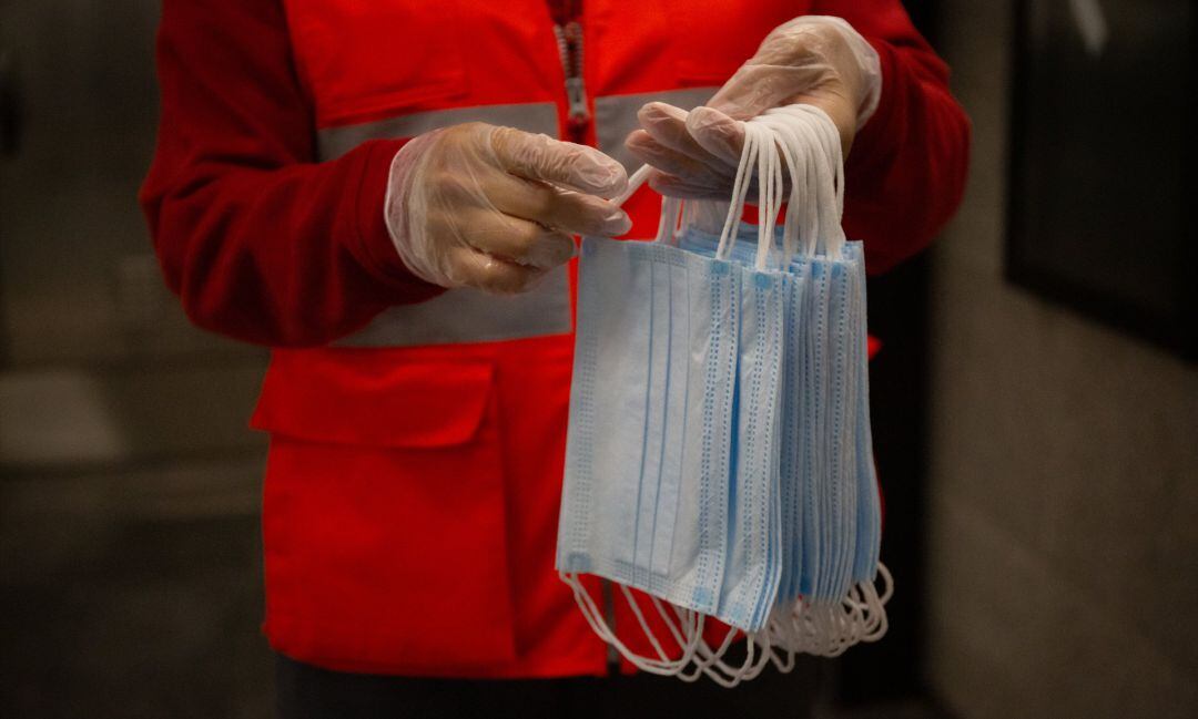 Archivo - Una voluntaria de Cruz Roja se prepara para entregar mascarillas en la estación catalana de Diagonal el día en el que se reactiva la actividad laboral no esencial en Catalunya