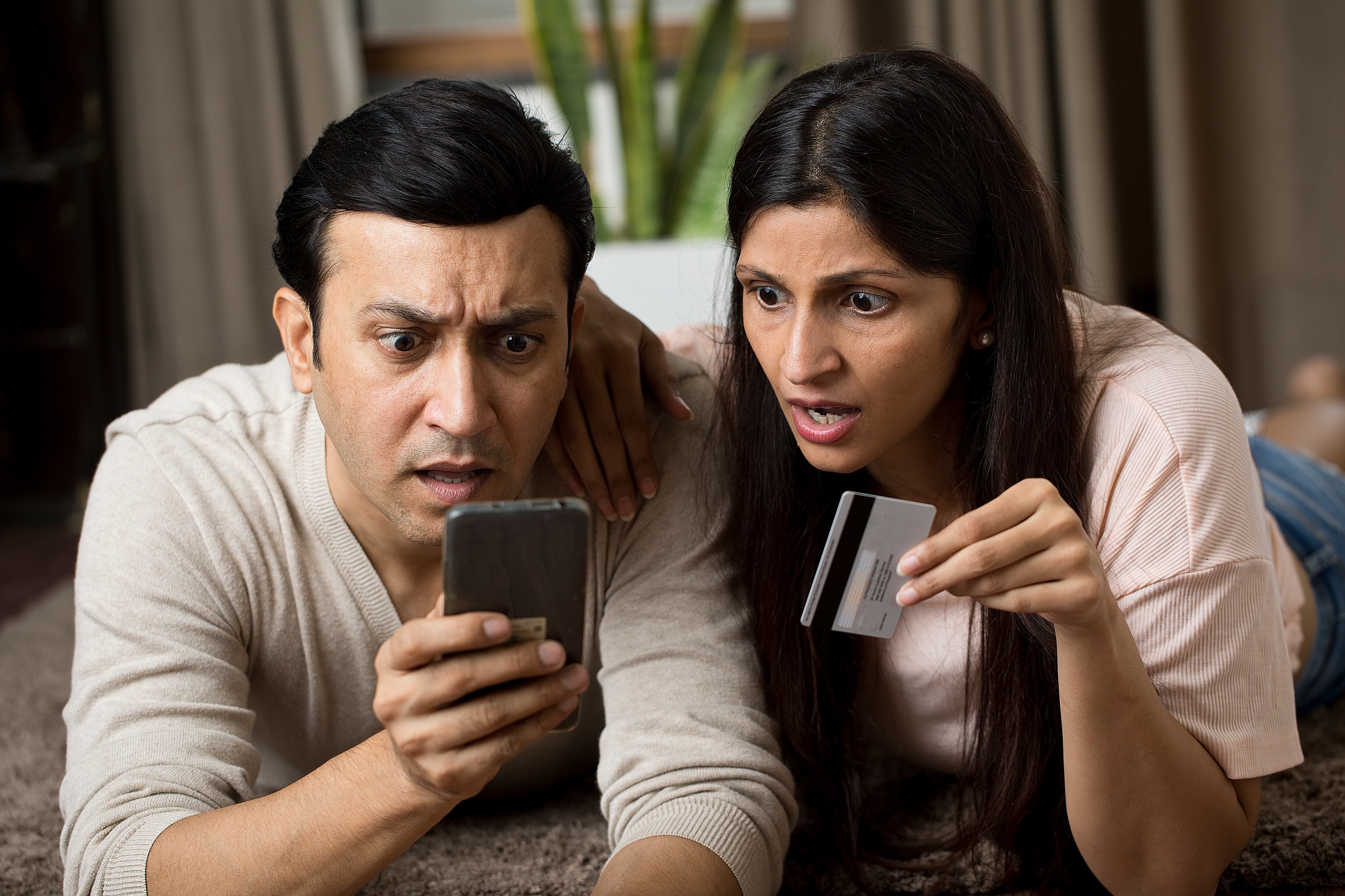 Una pareja mira sorprendida su móvil tras una compra online.