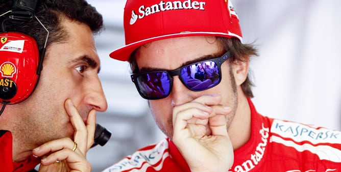 El piloto español de Fórmula Uno de la escudería Ferrari, Fernando Alonso (dcha), conversa con un miembro del equipo en el garage, durante la tercera y última sesión de entrenamientos libres para el Gran Premio de China que se disputa en Shanghái