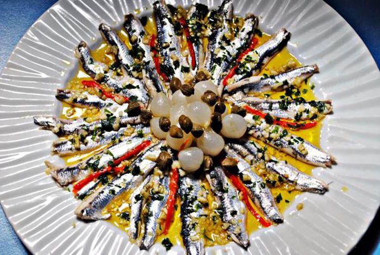 Boquerones del Cantábrico marinados con cebollitas y alcaparras.