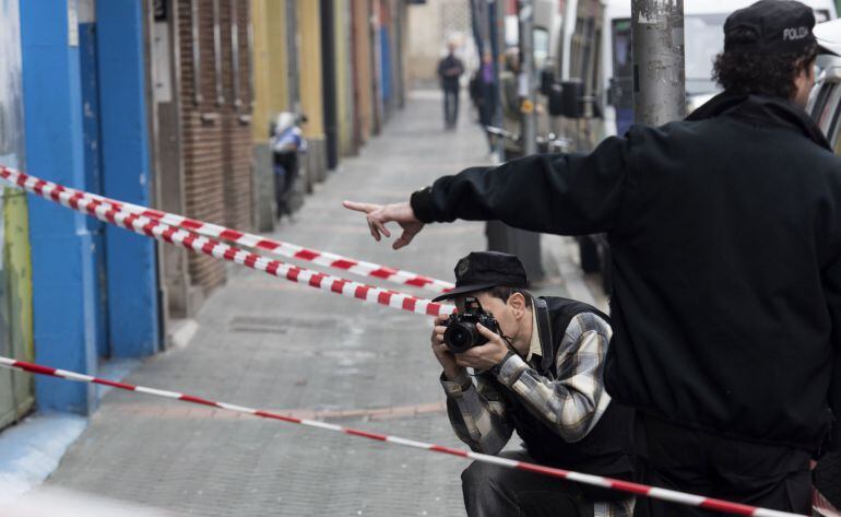 Un ertzaina toma fotografías en la entrada del domicilio del número 14 de la calle Libertad de Vitoria en el que un hombre de 30 años ha arrojado por la ventana a la hija de 17 meses de su pareja