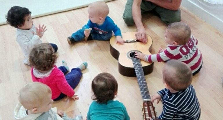 Niños experimentan con una guitarra.