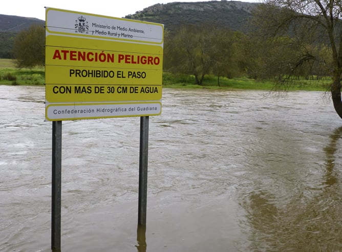 Un cartel de la Confederación Hidrográfica del Guadiana recomienda no cruzar el cauce crecido del río en Luciana (Ciudad Real).