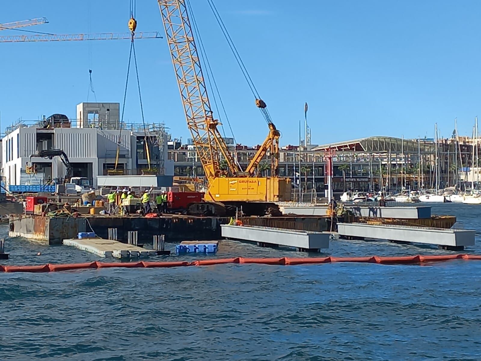 Los operarios trabajan en la instalación de una viga en la estructura de la Isla de la bocana del puerto de Alicante