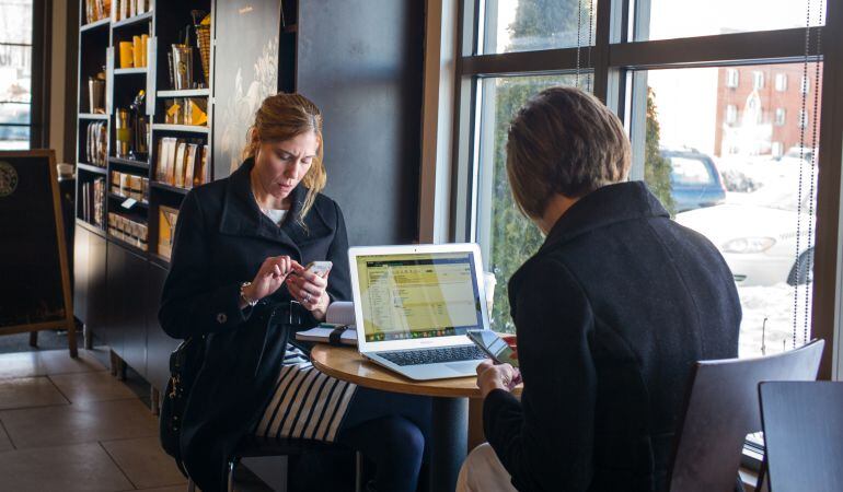 Dos personas practican el &#039;phubbing&#039; en un lugar público.