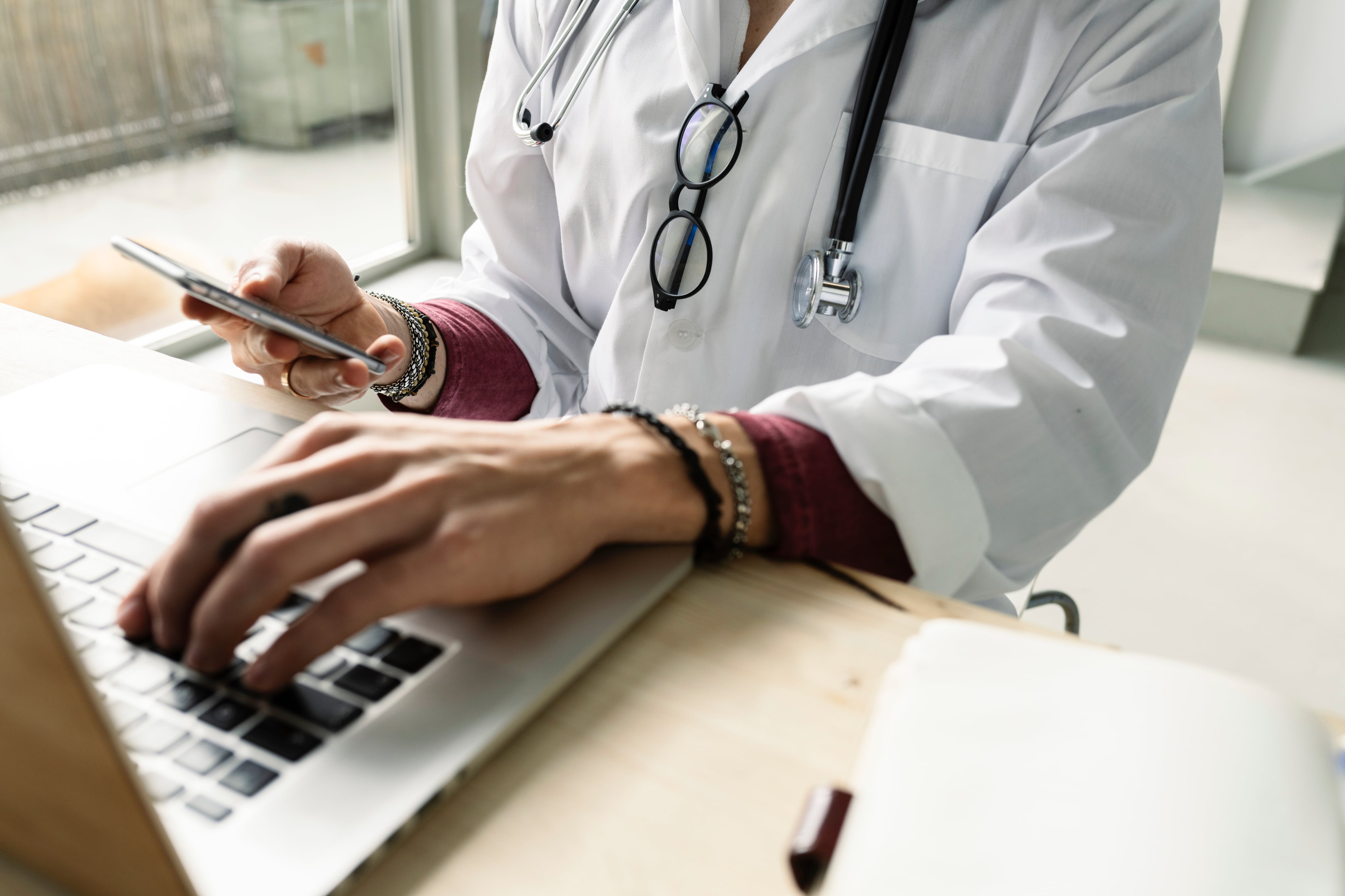 close-up of a female doctor using computer and smartphone