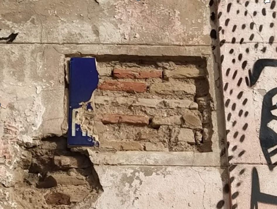 Restos de una placa cerámica rotuladora de principios del siglo XX expoliada en una fachada ruinosa de la Cruz Cubierta.