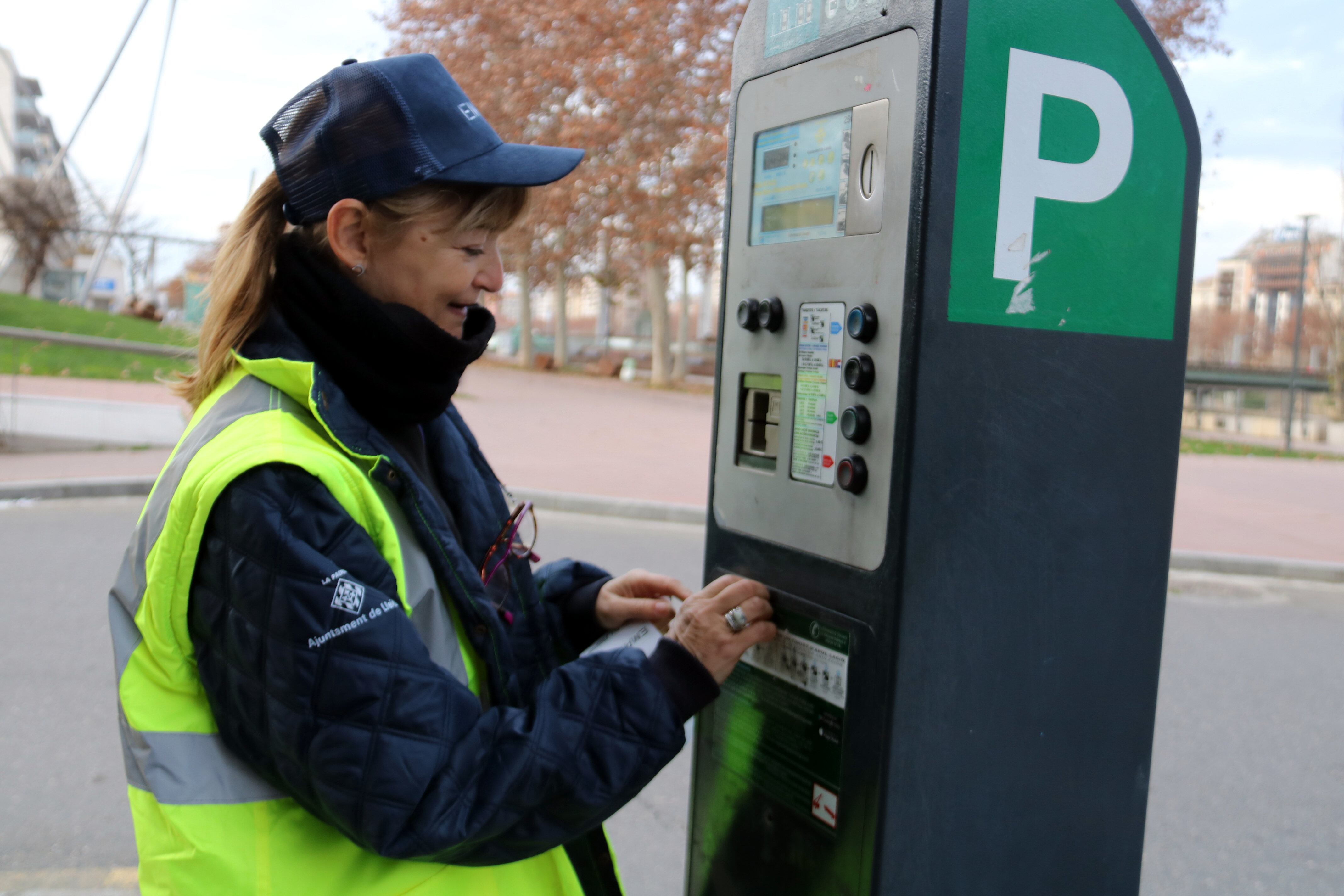 A Lleida ha canviat la gestió de la zona blava, que ara és municipal. A la foto, una vigilant canviant l'adhesiu que identifica que el parquímetre passa a ser gestió de l'Empresa Municipal d'Agenda Urbana. Foto: ACN.