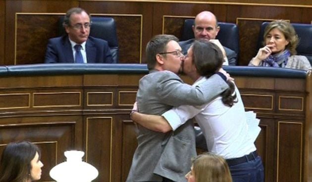 El líder de Podemos, Pablo Iglesias y el de En Comú Podem, Xavier Doménech, se besan en los labios al término de la intervención del diputado catalán.