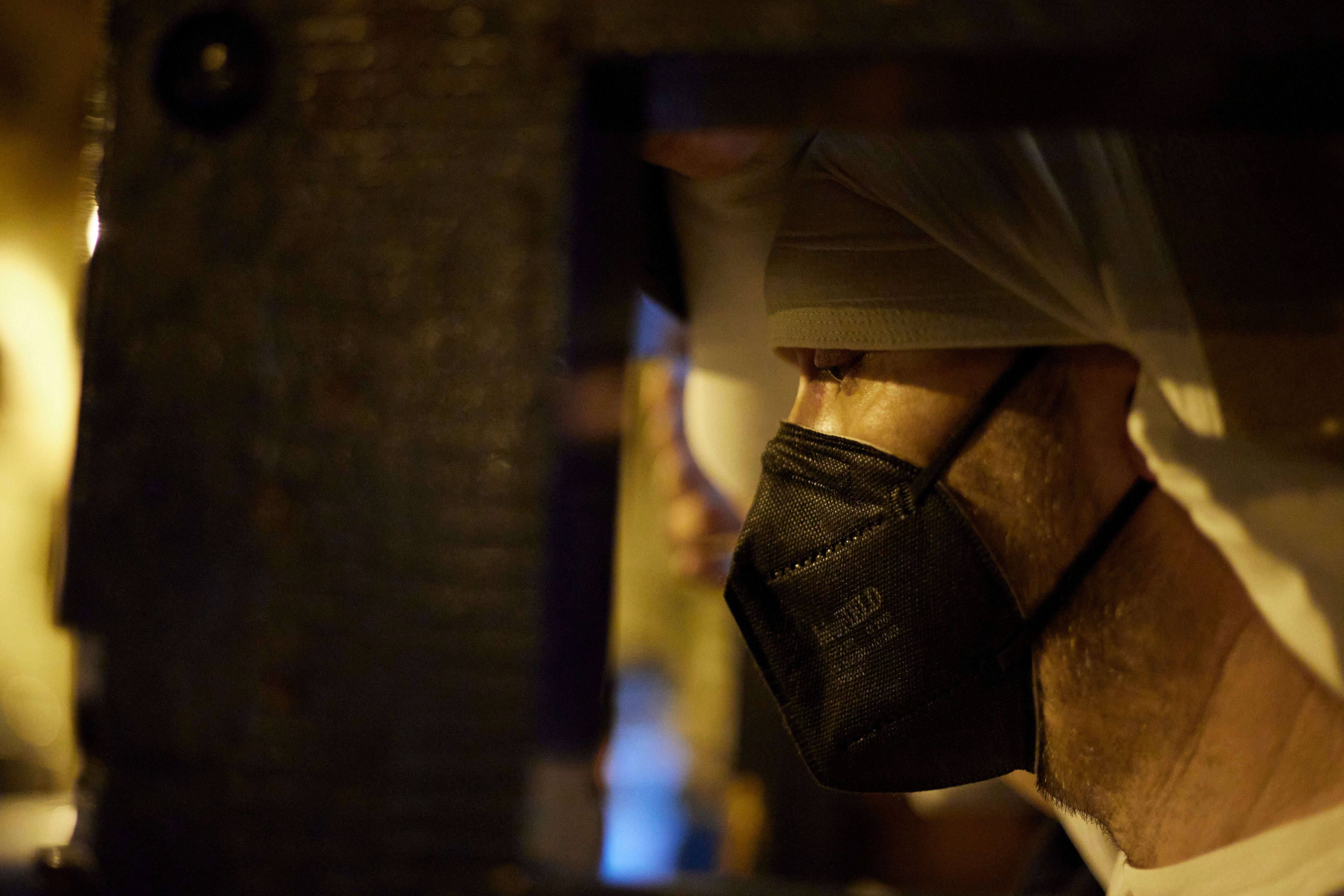 Un costalero carga un paso de Semana Santa con la mascarilla puesta