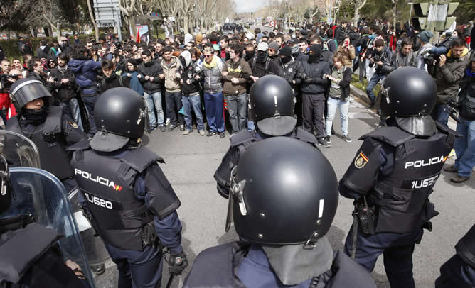 Un grupo de estudiantes corta el tráfico en la Avenida Complutense, vigilados por agentes de policía, que llevan material antidisturbios