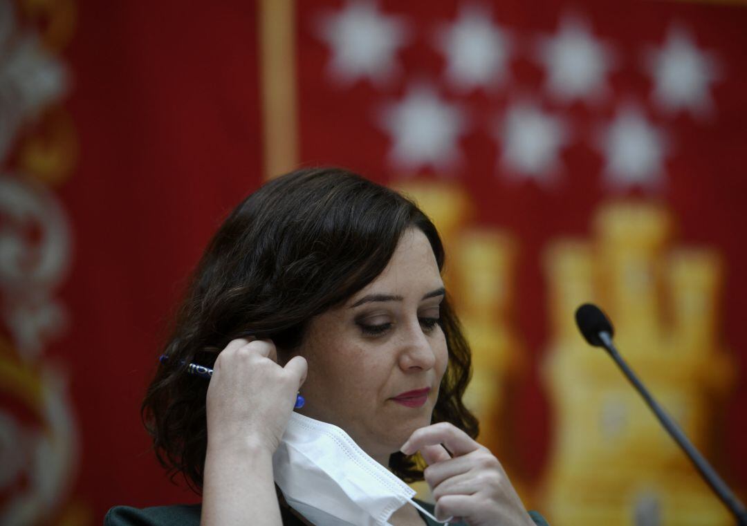 La presidenta de la Comunidad de Madrid, Isabel Díaz Ayuso, se quita la mascarilla antes de presentar la estrategia de continuidad del Covid-19