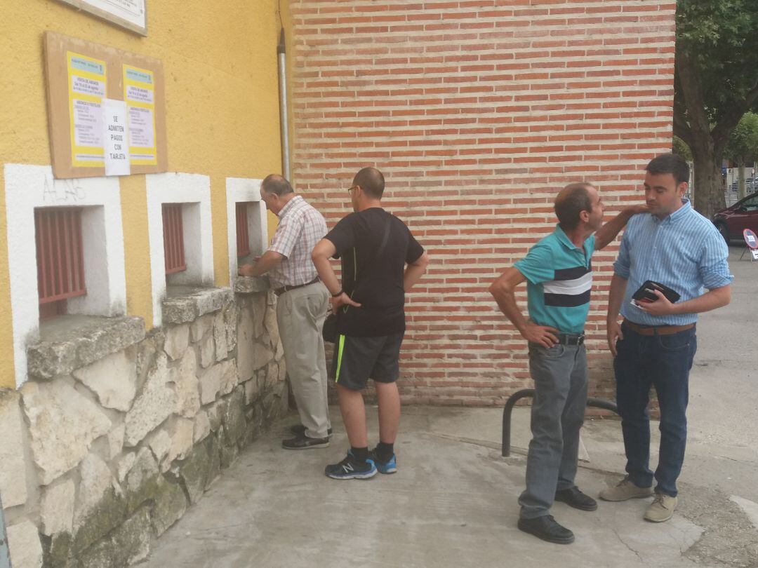 El alcalde de Cuéllar, Carlos Fraile, espera en la taquilla de la plaza de toros hablando con un vecino para adquirir su abono