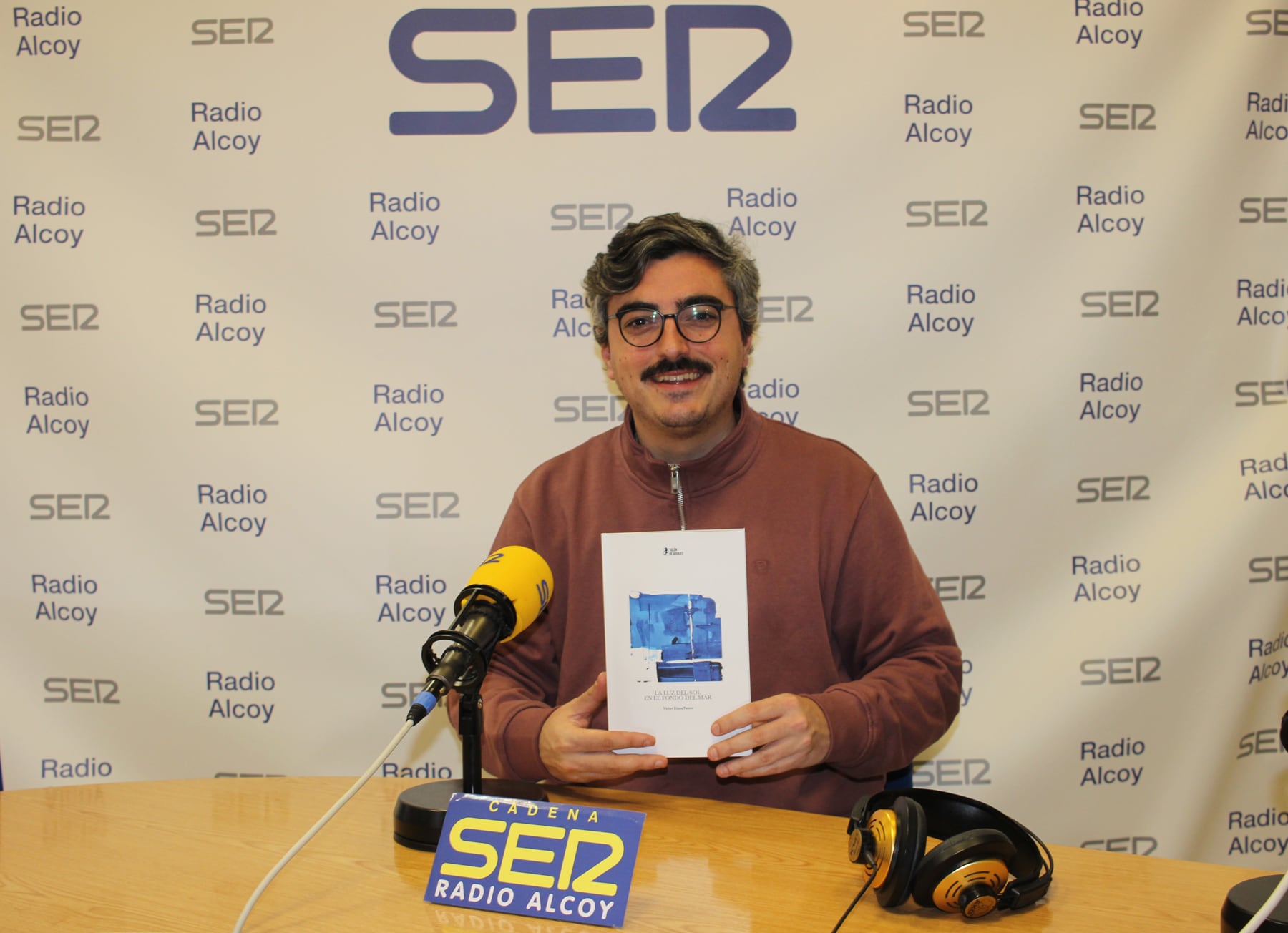 Víctor Riaza, amb un exemplar del primer llibre de poemes que ha escrit, en l'estudi central de Radio Alcoy