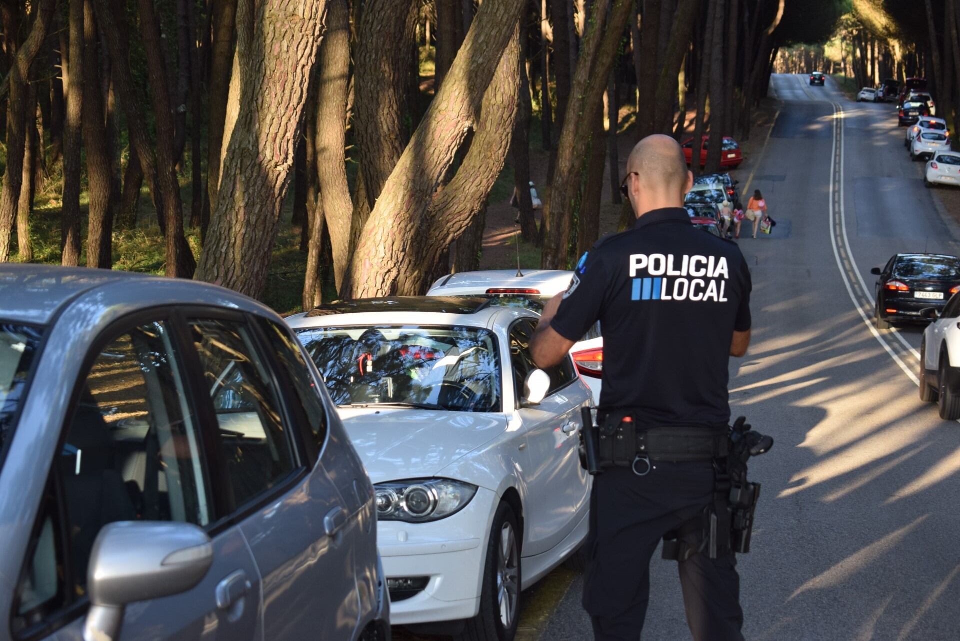 Un policía local sancionando a los coches mal estacionados en la carretera de acceso a las playas de Liencres.