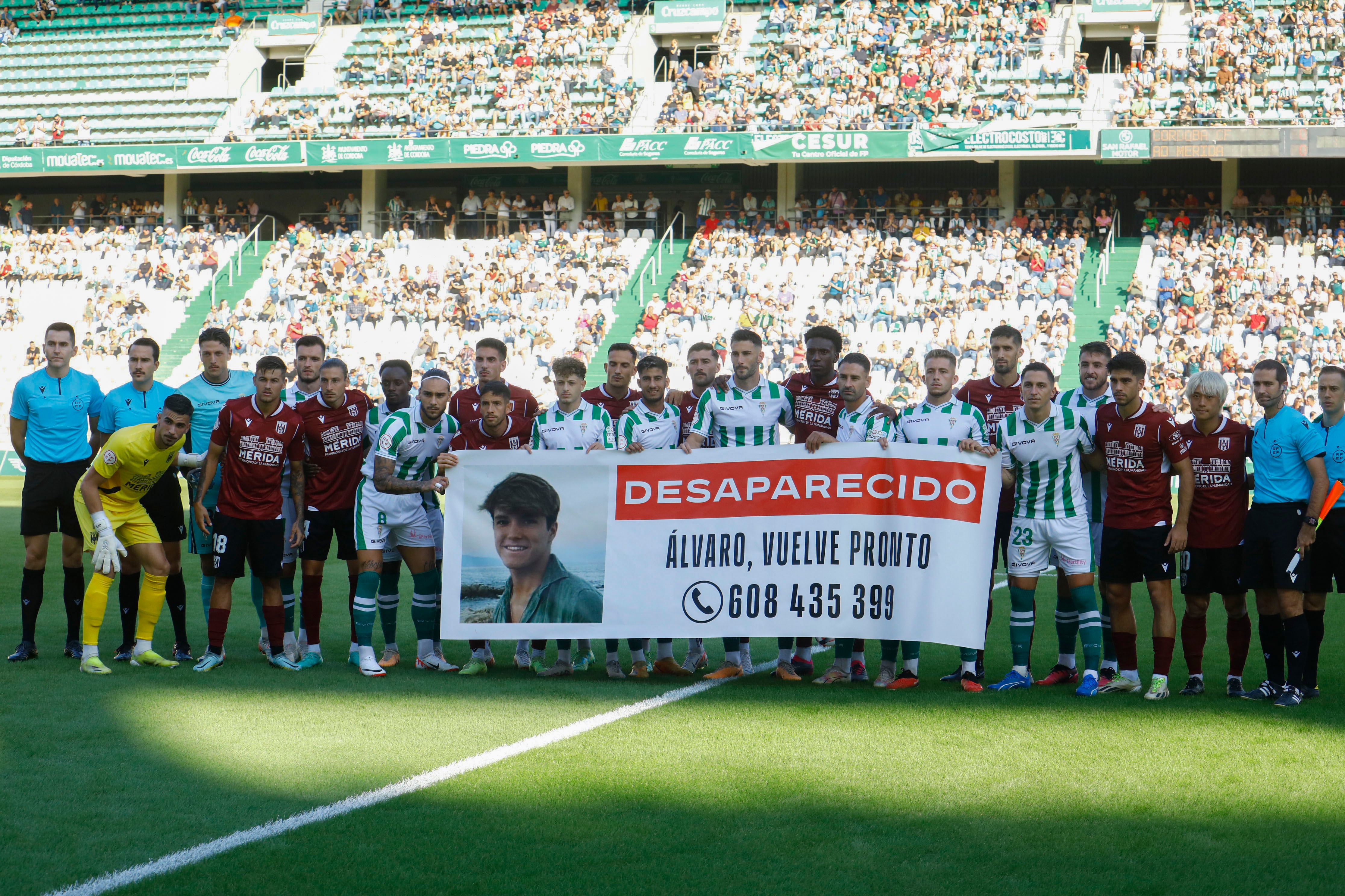 Córdoba 14/10/2023. Jugadores del Córdoba y el Mérida sostienen una pancarta en apoyo a la búsqueda del joven Álvaro Prieto, el chico de 18 años desaparecido en Sevilla y perteneciente al equipo juvenil del Córdoba CF, este sábado en el estadio del Arcángel antes de su encuentro. EFE/Salas
