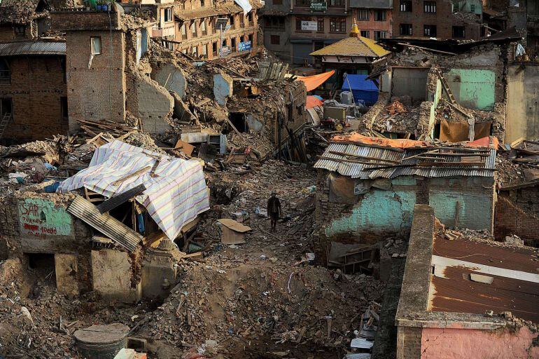 A Nepalese man walks past damaged houses following an earthquake in Kathmandu on May 26, 2015. The April 25 disaster was followed by another massive quake on May 12, which sent shockwaves through the Himalayan nation, as the twin tremors killed over 8,600