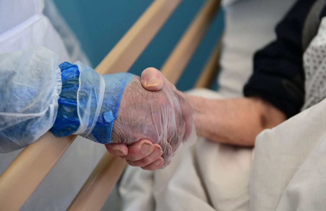 Imagen de un hombre sujetando la mano de una mujer ingresada. 