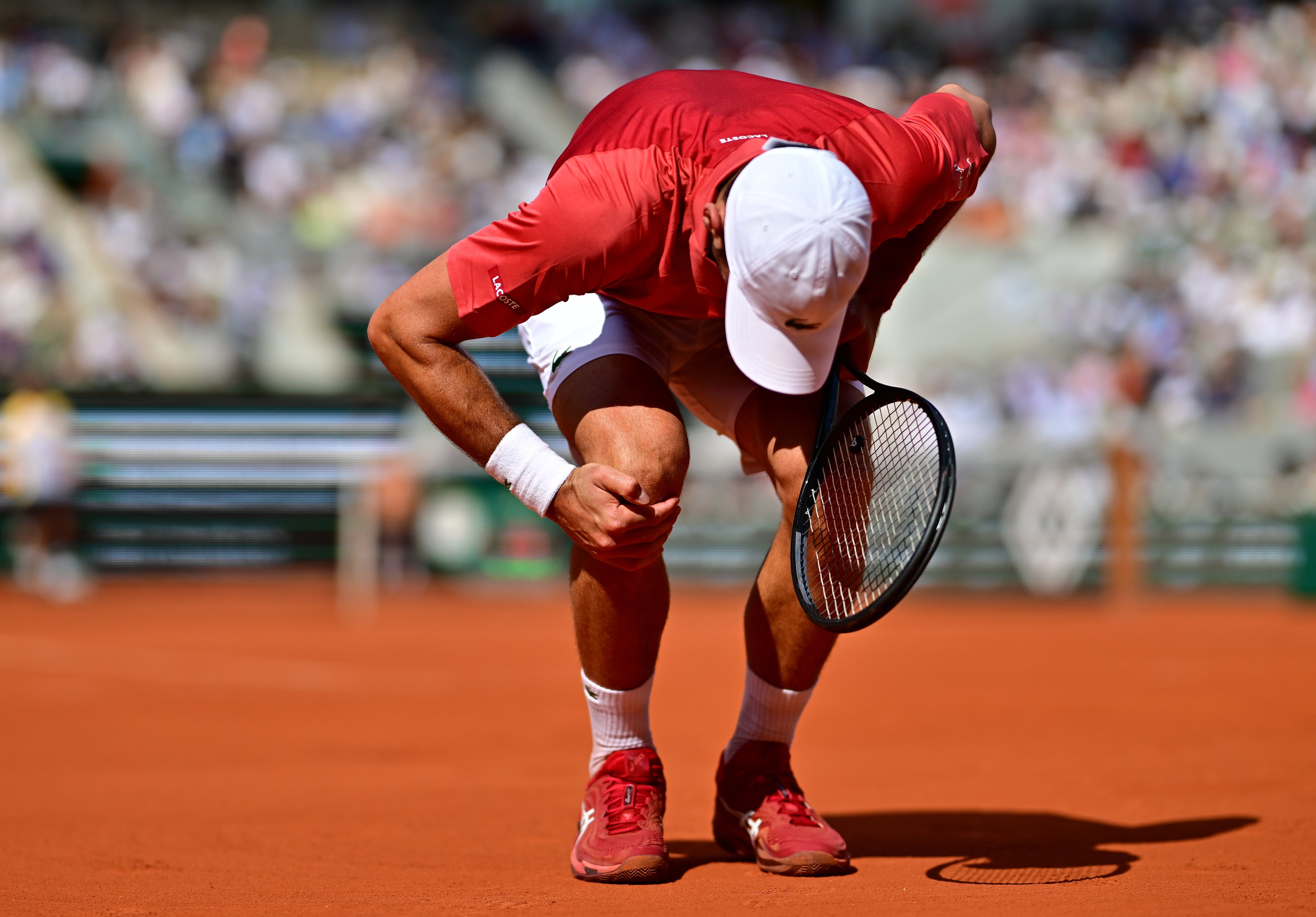 Novak Djokovic se duele de su rodilla derecha durante el partido de octavos de final de Roland Garros ante el argentino Cerúndolo