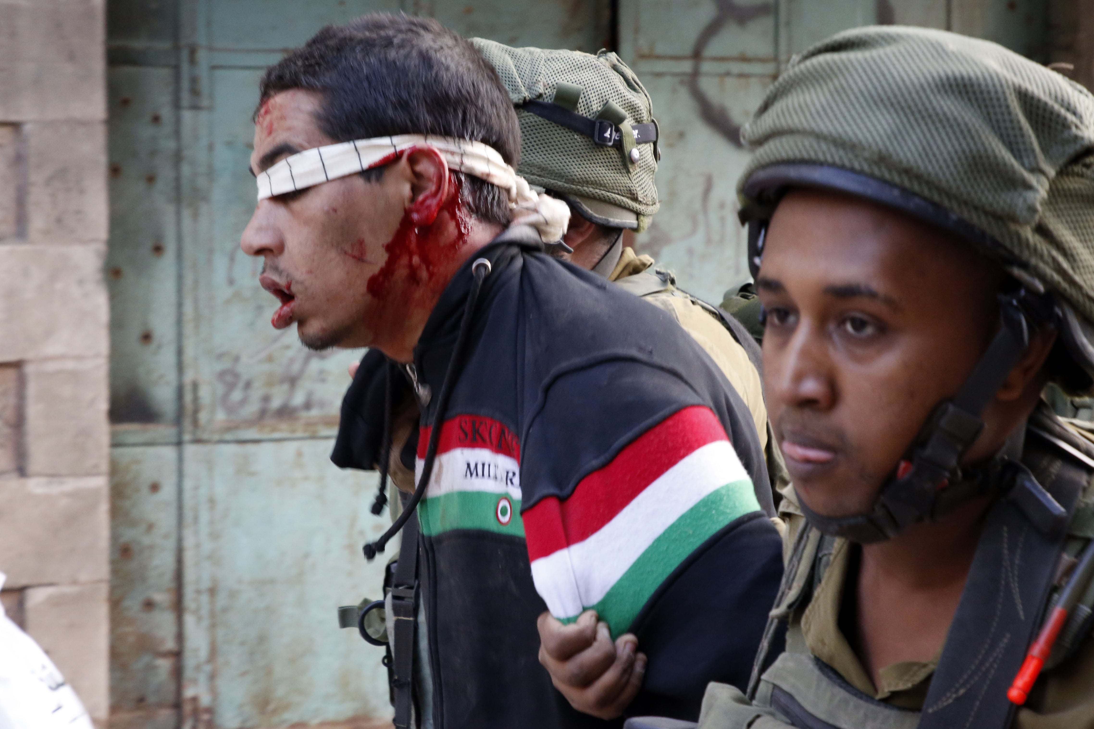 Dos soldados israelíes arrestan a un joven palestino, después de que lanzase piedras al paso de una procesión judía, en noviembre de 2017