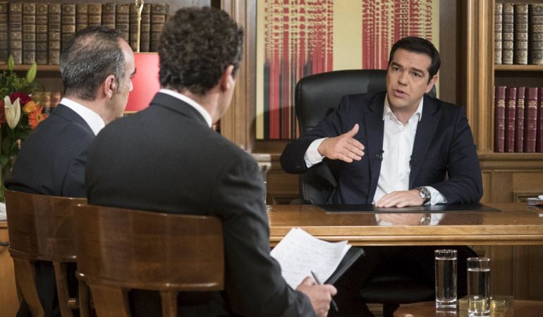 El primer ministro griego, Alexis Tsipras, habla con dos perodistas en su despacho.