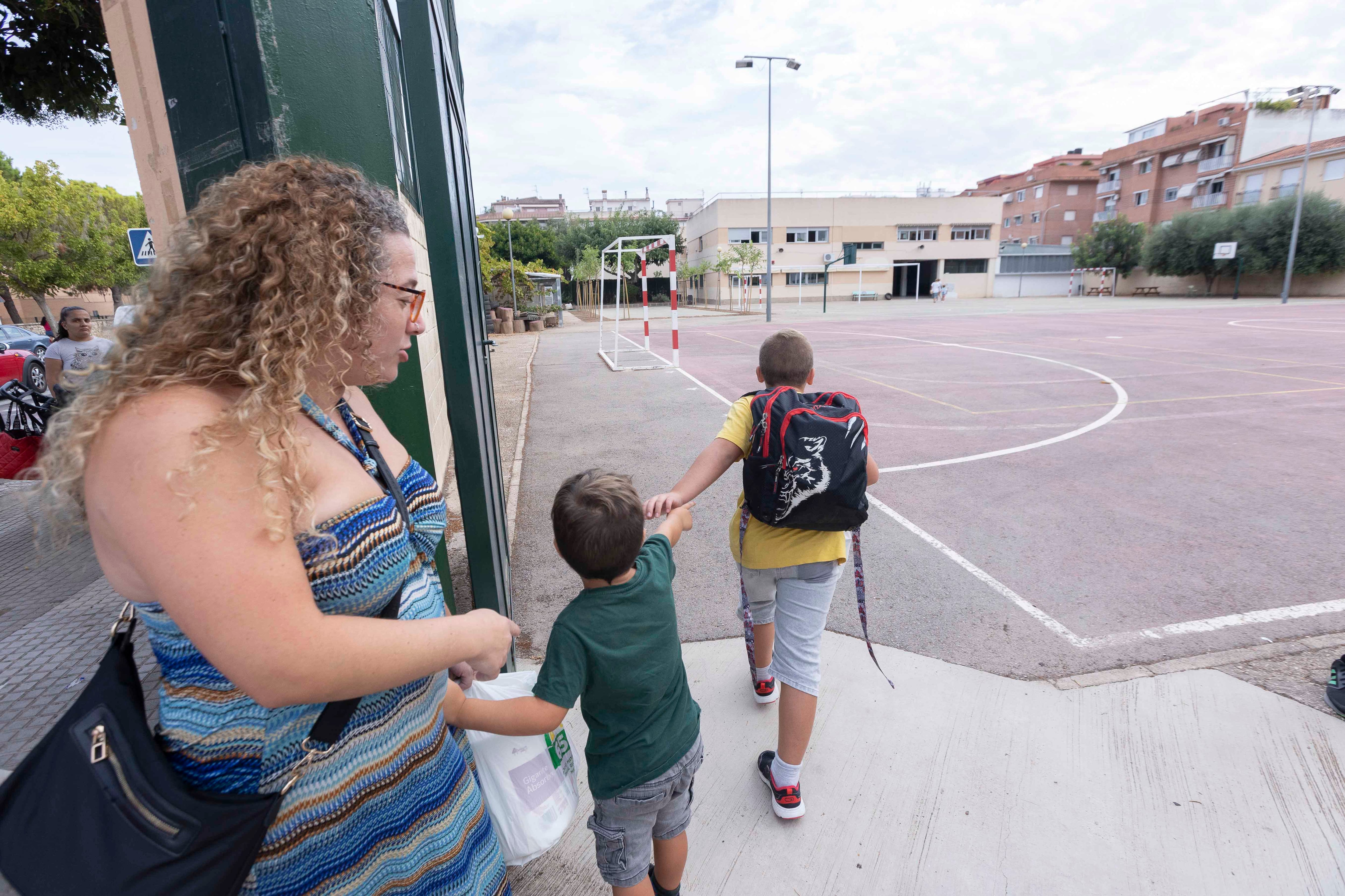 Una mujer acompaña a dos pequeños a la entrada de un colegio de Gandia.