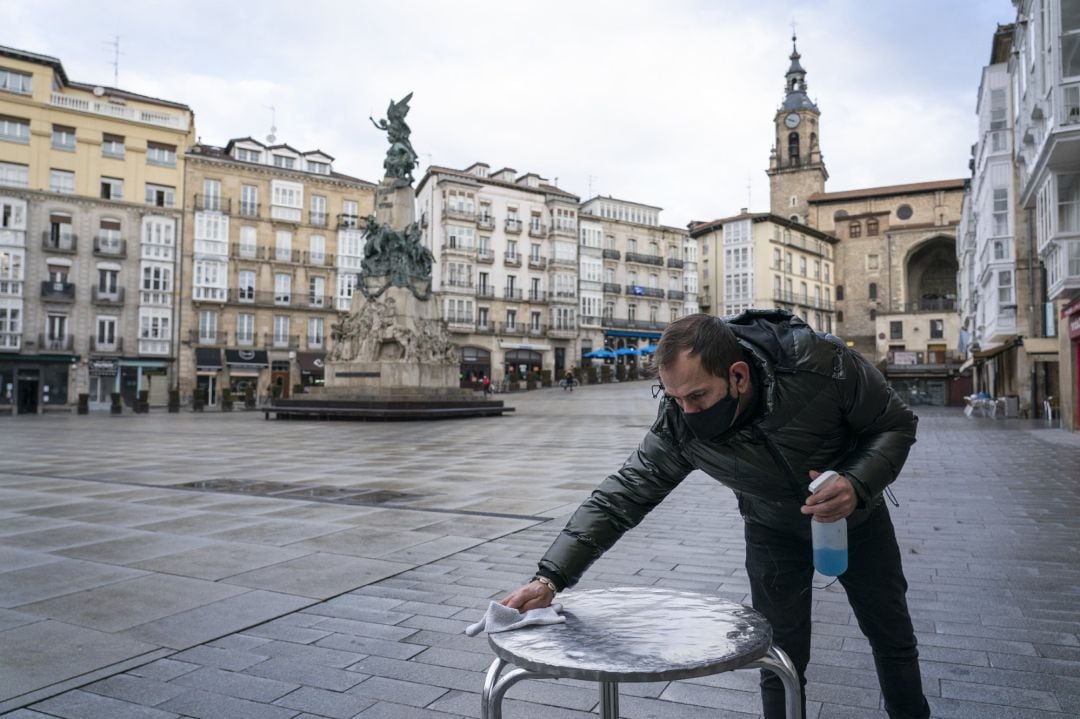 Un camarero limpia una mesa de la terraza de su cafetería durante una jornada marcada por la reapertura de los establecimientos