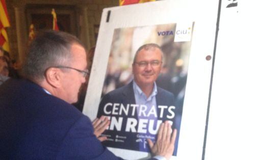Carles Pellicer (CiU), penjant el cartell electoral.
