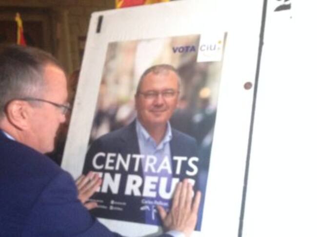 Carles Pellicer (CiU), penjant el cartell electoral.