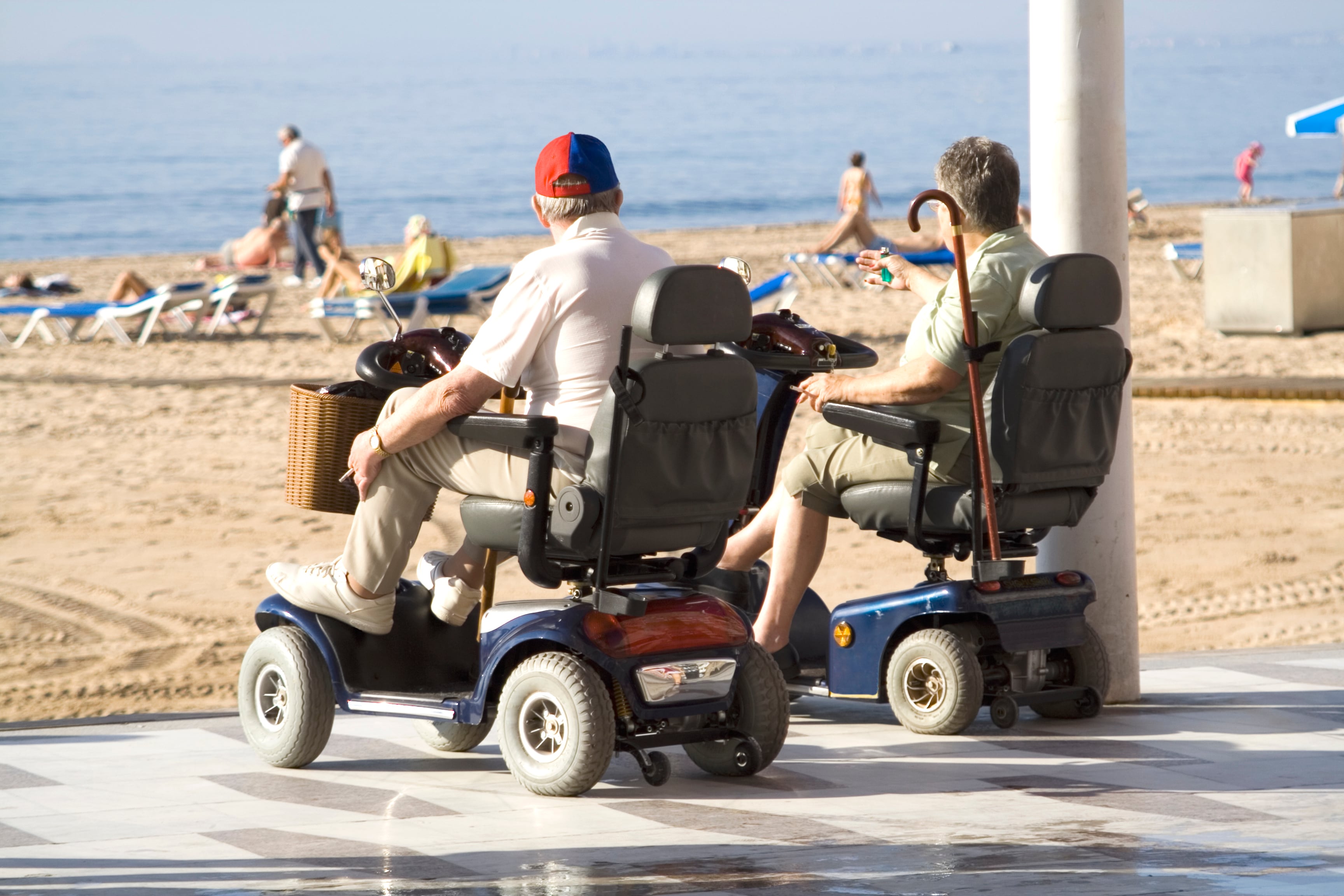 Una pareja en silla de ruedas, frente a la playa.