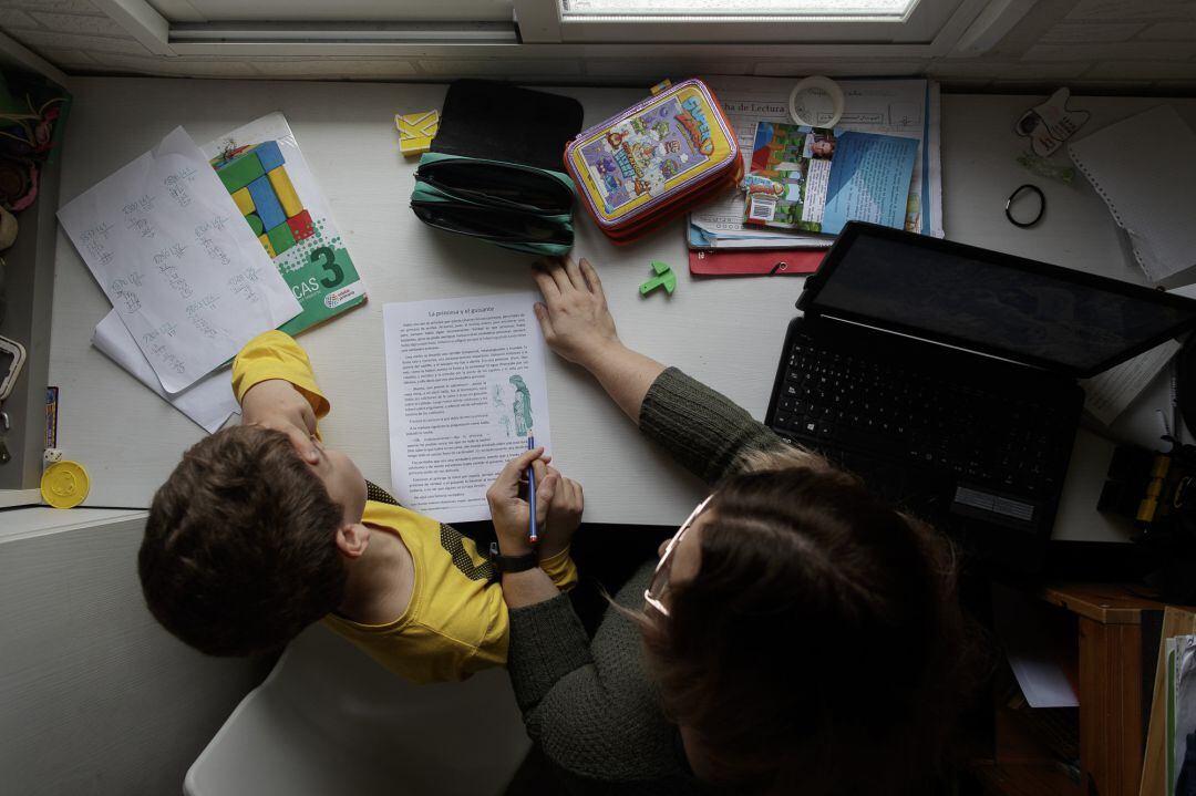 Un niño estudia y hace los deberes en casa con la ayuda de su madre