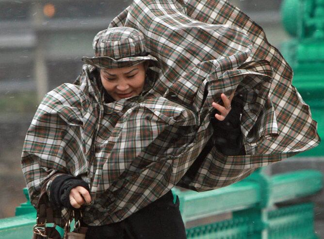 Una mujer se protege del viento y de la lluvia en San Sebastián