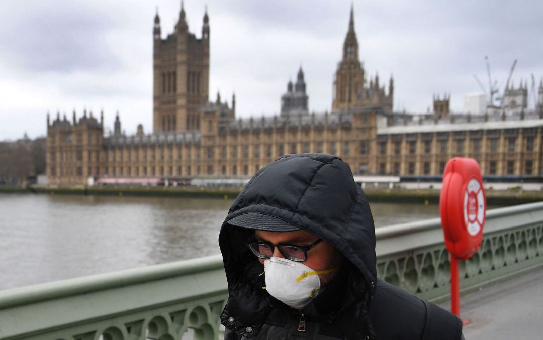 Un hombre con mascarilla paseando por el puente junto al Parlamento británico