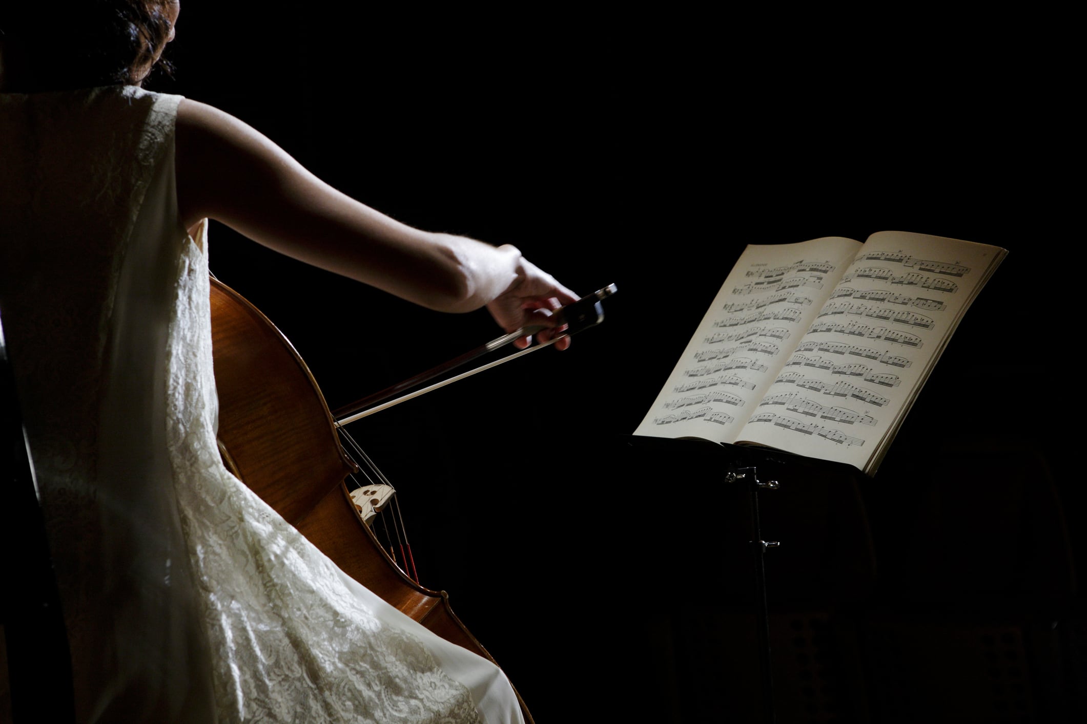 Una mujer chelista tocando delante de una partitura