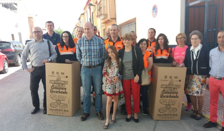 Celia, en el centro entre su madre y el alcalde, presentan los contenedores de latas