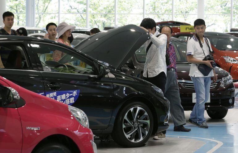 Varias personas observan diferentes modelos de Toyota en un concesionario en Tokio (Japón).