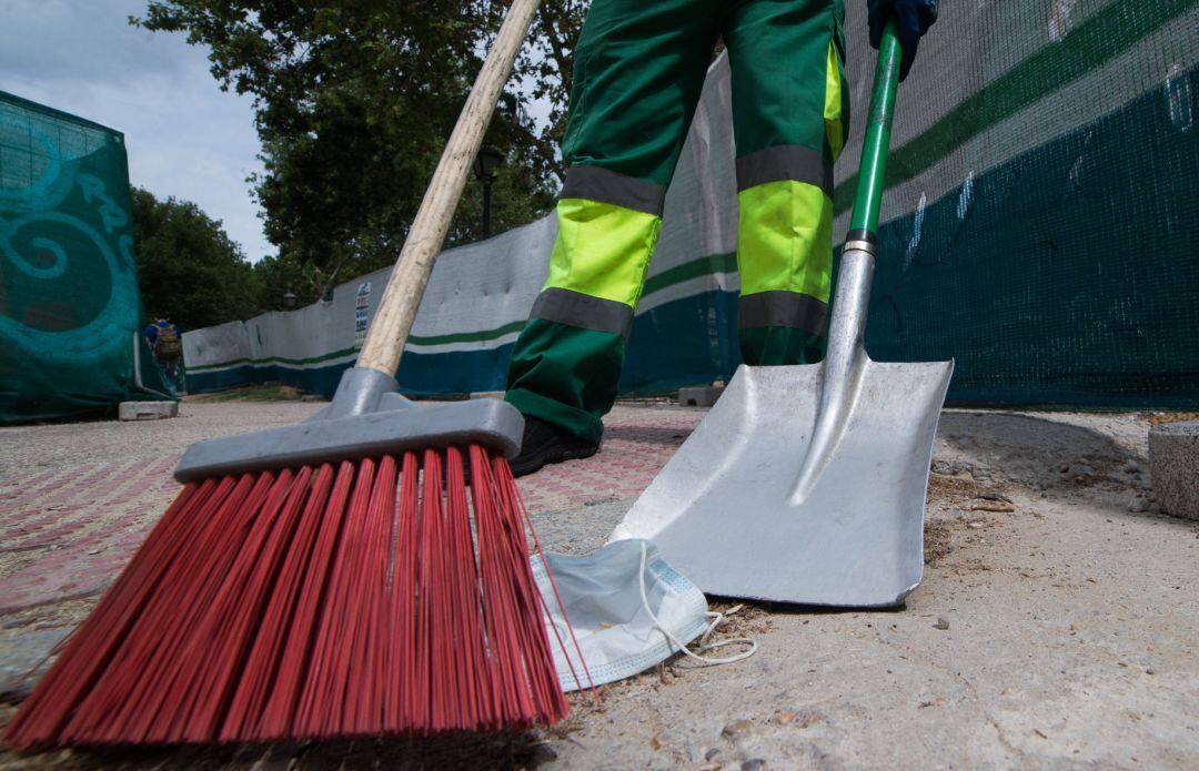 Un trabajador de la limpieza recoge una mascarilla tendida en el suelo de la capital durante el segundo día de la Fase 1.