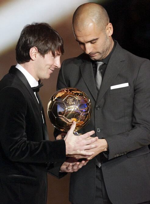 El futbolista argentino del F.C. Barcelona Lionel Messi recibe el trofeo al mejor jugador de manos del entrenador de su equipo, Pep Guardiola, durante la gala del Balón de Oro de la FIFA que se ha celebrado en el Palacio de Congresos de Zúrich