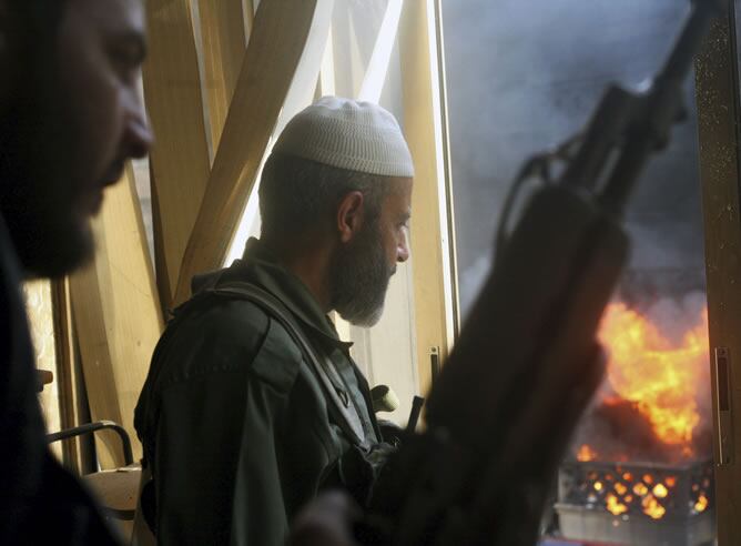 Dos soldados de las Fuerzas Armadas Sirias pertenecientes al grupo Al Tawid observan una explosión durante los enfrentamientos con miembros del ejército del gobierno sirio, en Alepo