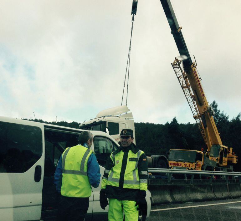 Operarios gestionando el tráfico en la zona con el camión suspendido de la grúa detrás