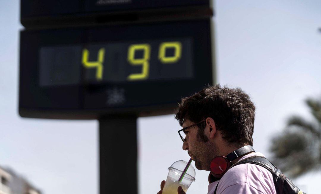  Un hombre toma una bebida junto a un termómetro de Córdoba en otra jornada marcada por la ola de calor en la que hay previsiones de que las temperaturas alcancen los 47 grados en el Valle del Guadalquivir. 