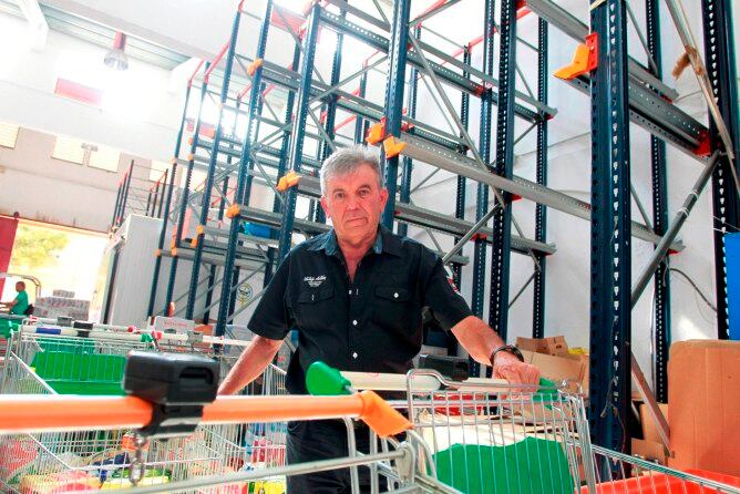 El presidente del banco de alimentos, Jaime Serra, posa con las estanterías del banco de alimentos vacías