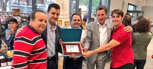 Representantes del proyecto de crianza de abejas en Leganés posan con el premio que les reconoce como la mejor miel clara de la región