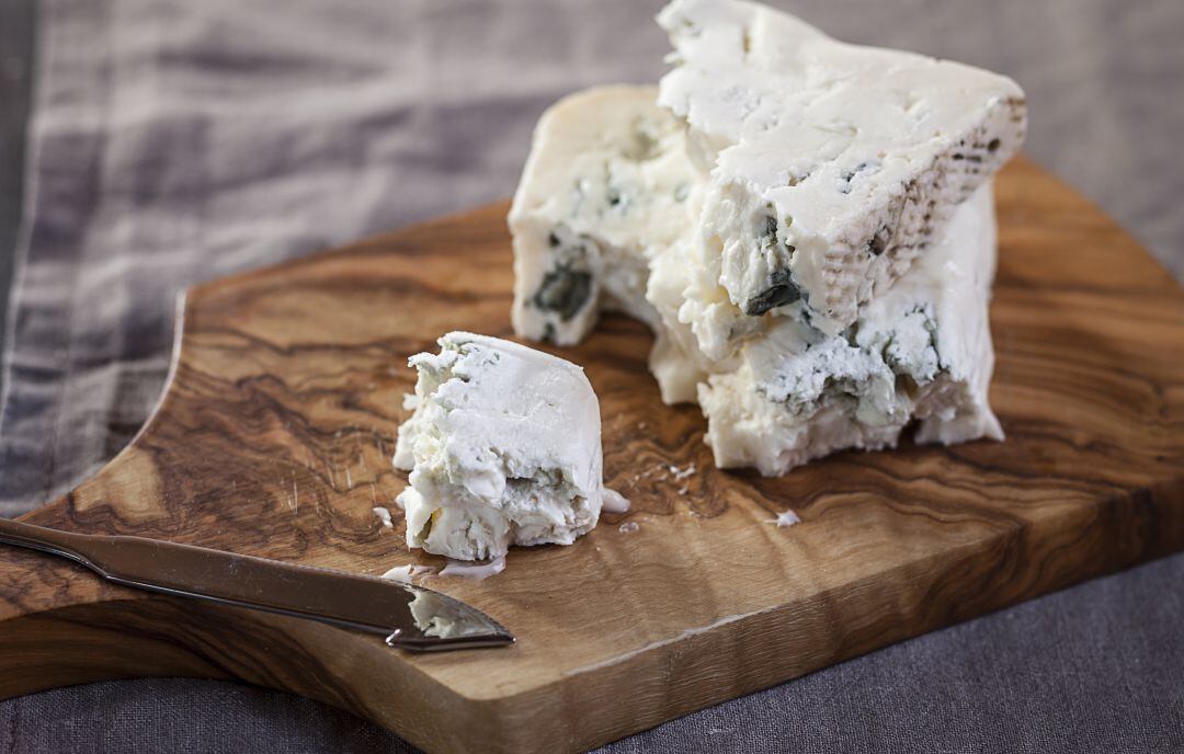 Pieza de queso gorgonzola en una tabla de cortar.