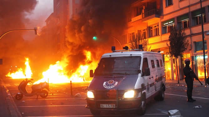 La Ertzaina hace guardia frente a una barricada incendiaria en el barrio de Rekalde