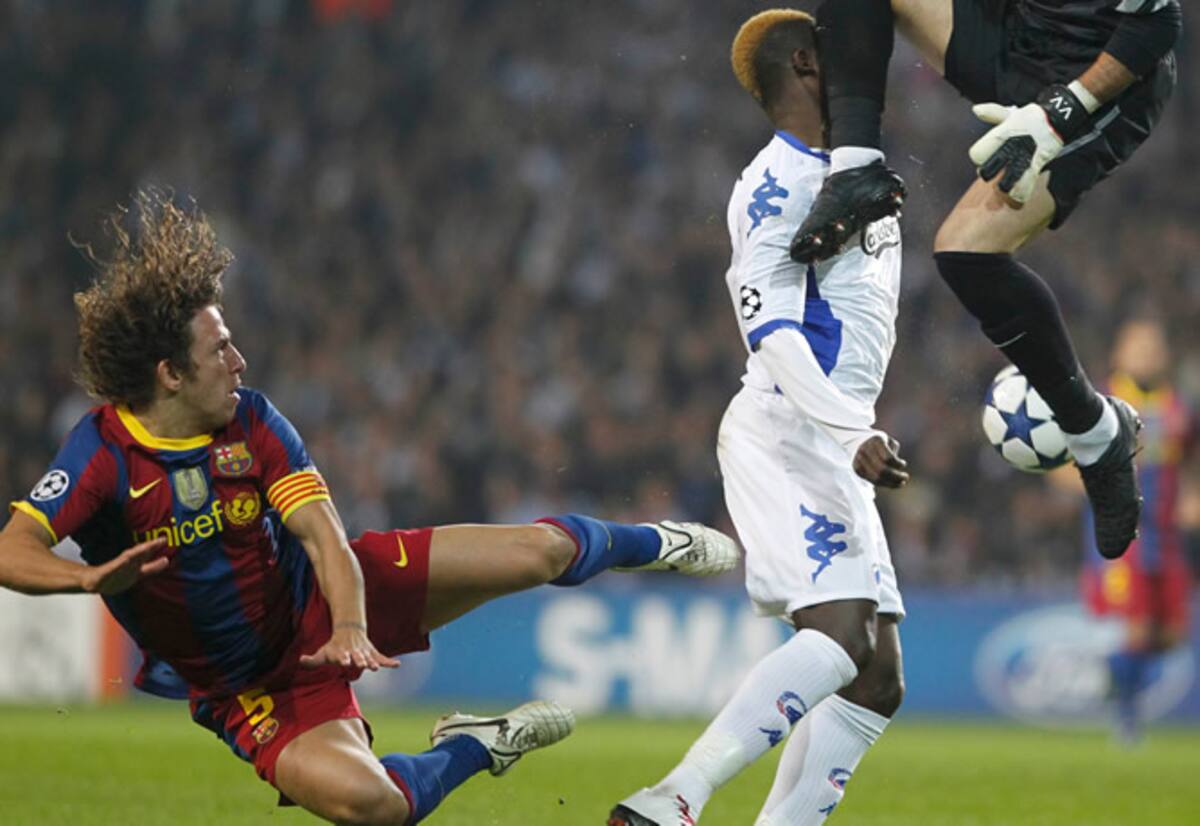 El jugador del Copenhague N'Doye choca en una acción con el guardameta del Barcelona Víctor Valdés