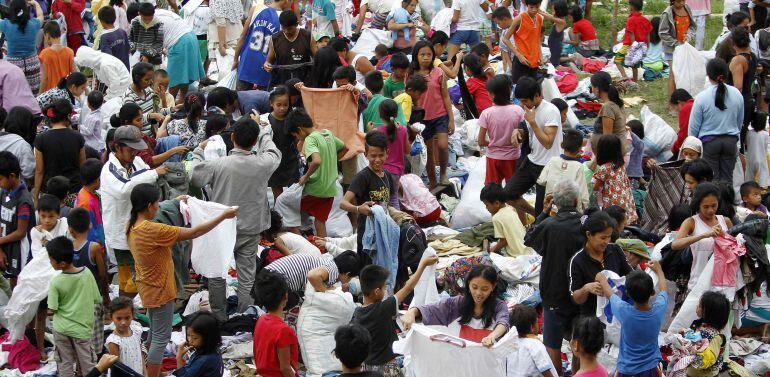 Niños y adolescentes ordenando ropa donada en un centro de evacuación donde se protegen del tifón Hagupit