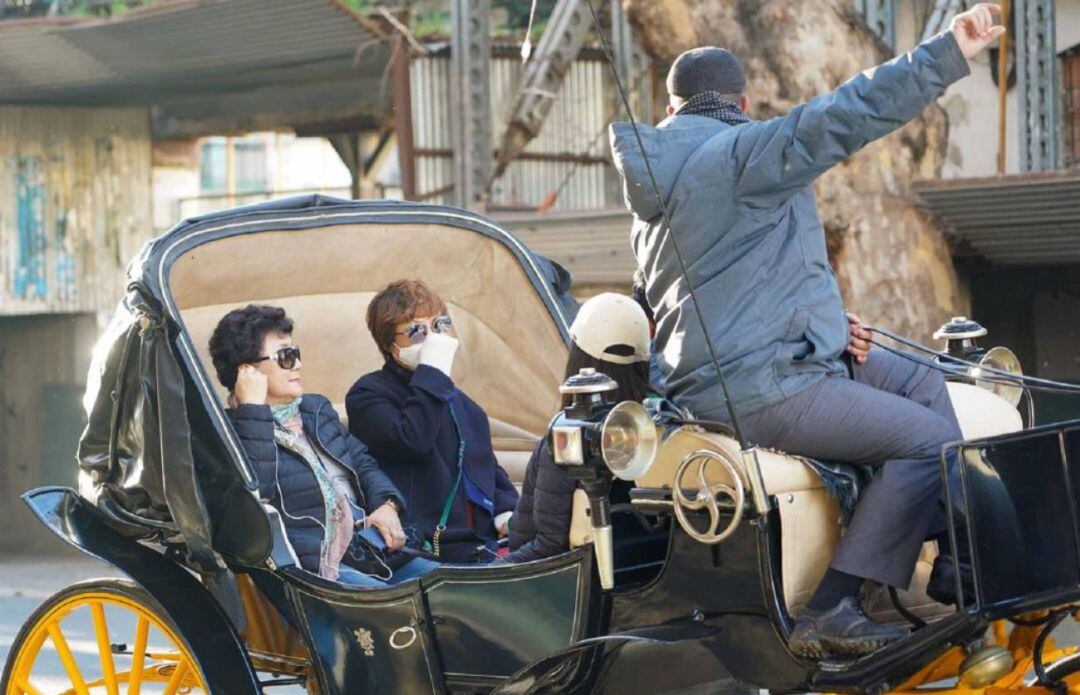 Dos turistas pasean a caballo por el centro de Sevilla.