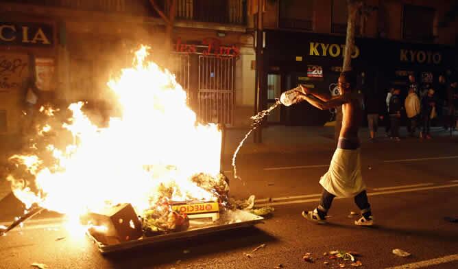 Un joven echa gasolina a un fuego provocado en plena calle de Barcelona en protesta por el desalojo de Can Vies